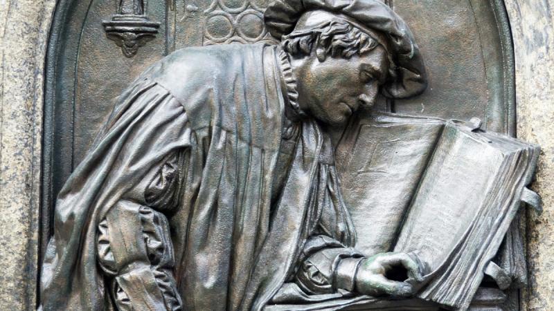 A statue depiction of Martin Luther turning a page of Scripture.