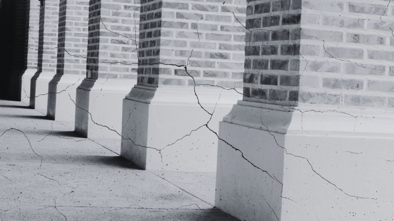 Brick columns of a seminary building with cracks in the foundation.
