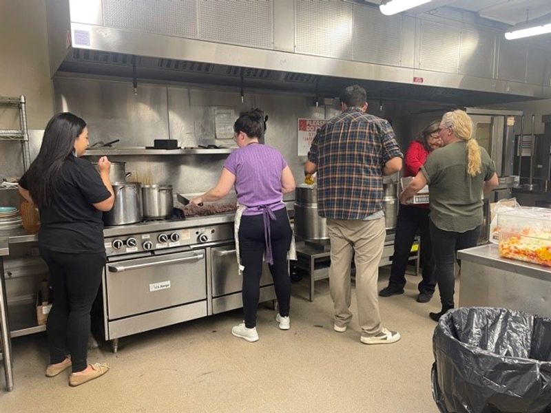 Volunteers preparing food together in a large kitchen.