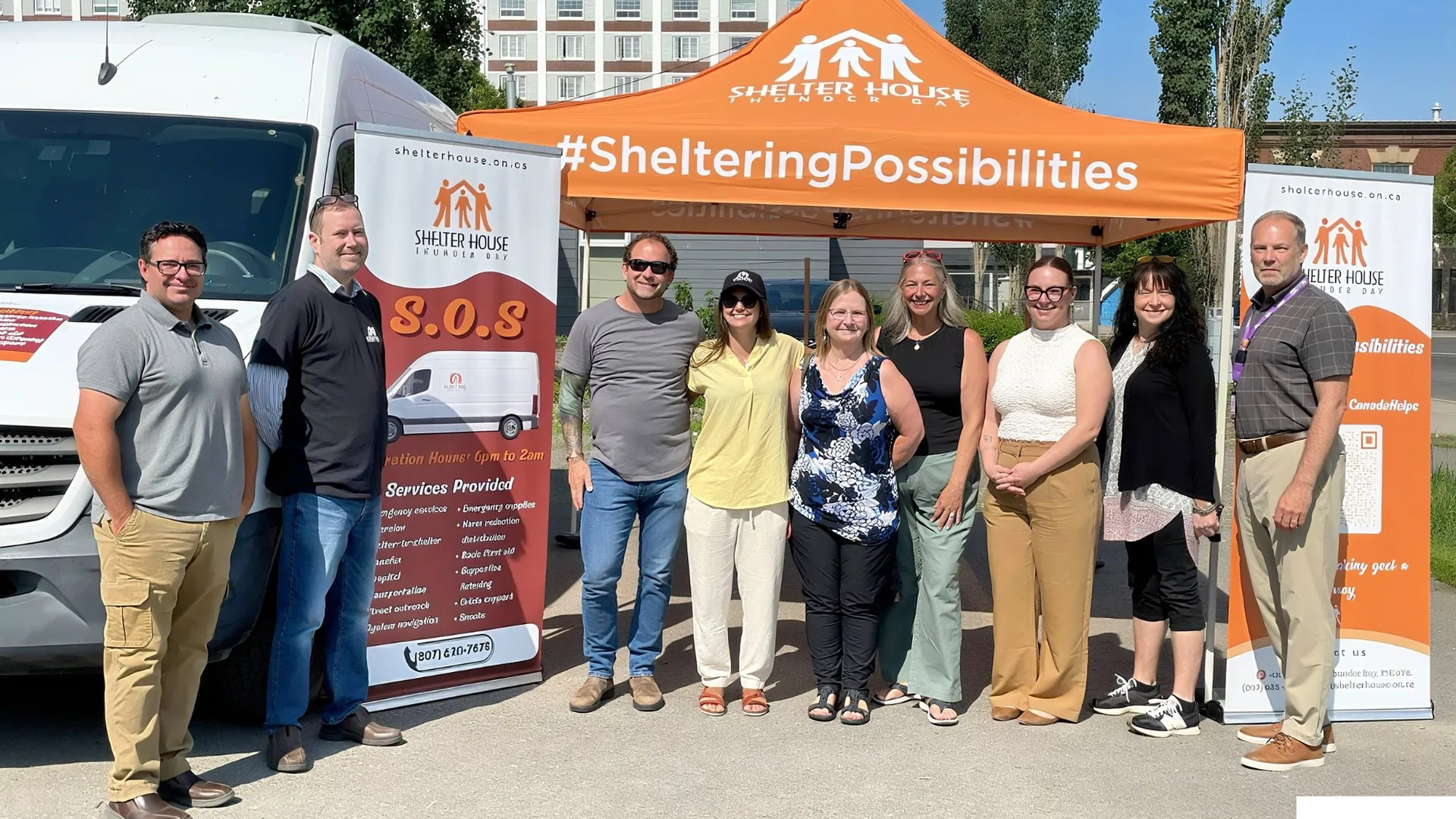 Shelter House Thunder Bay team members standing together outdoors under an orange Shelter House tent beside a service van.