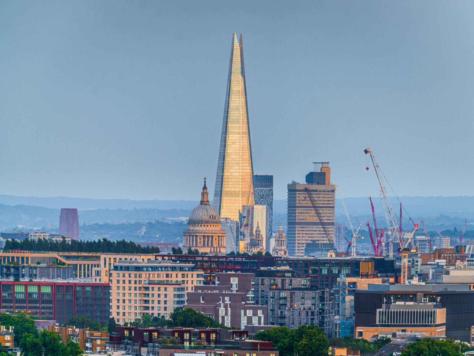 Golden Light reflects off the Shard in London, with St Pauls Cathedreal standing beside it from the viewpoint of Parliament Hill.