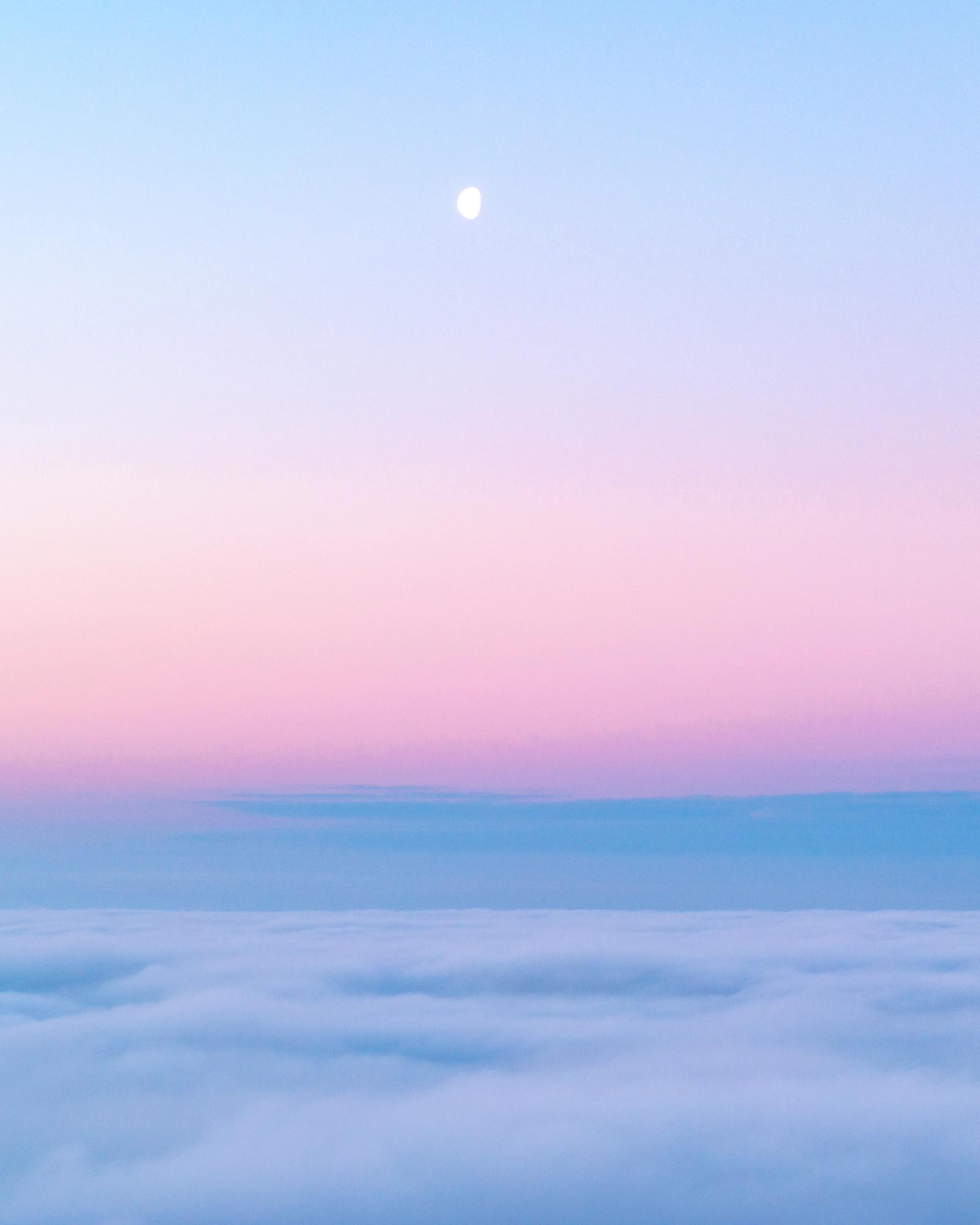 A temperature inversion buries the Thames Valley beneath a flat sea of cloud at dusk, the gibbous moon suspended in a sky grading from powder blue through rose to lavender. Shot from elevation above Abingdon-on-Thames, the compression between cloud ceiling and clear upper atmosphere creates a horizon line of unusual stillness. The near-total absence of hard edges gives the frame a quality closer to watercolour than photography.