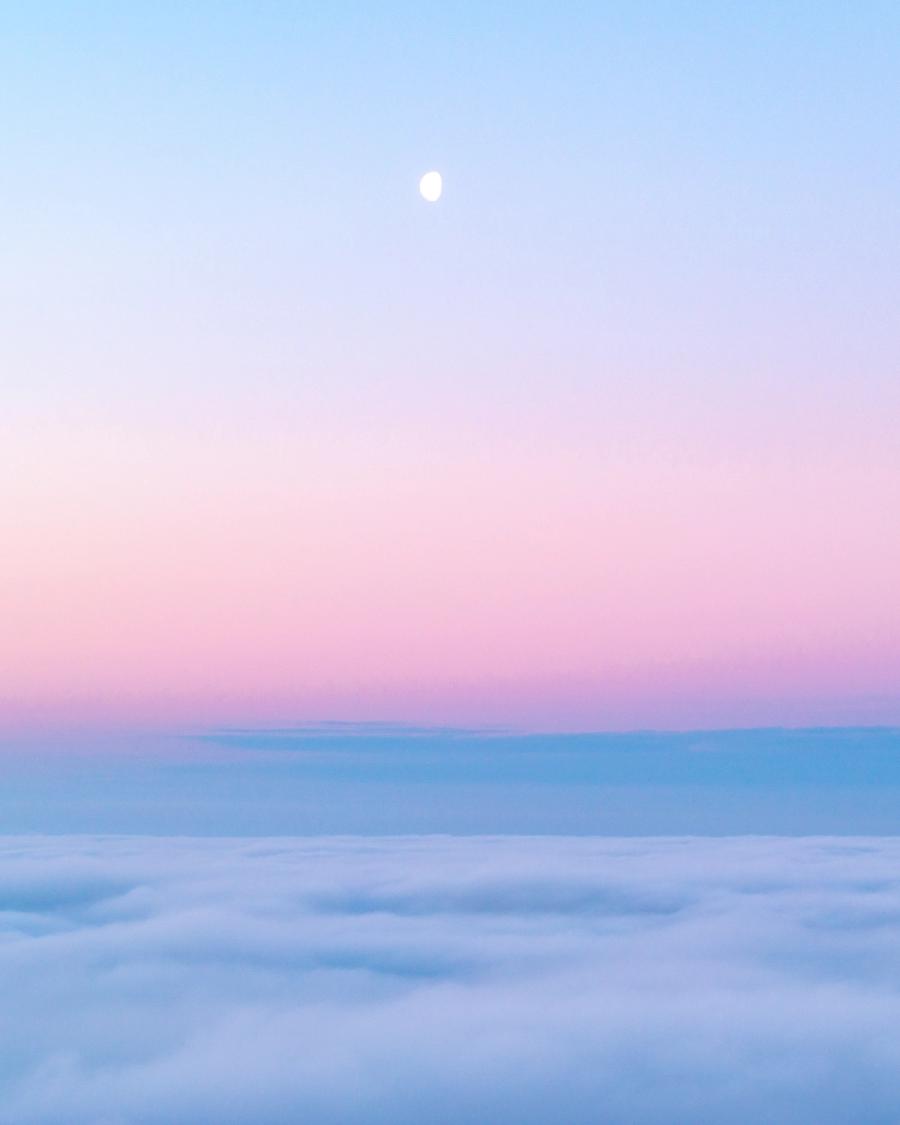 A temperature inversion buries the Thames Valley beneath a flat sea of cloud at dusk, the gibbous moon suspended in a sky grading from powder blue through rose to lavender. Shot from elevation above Abingdon-on-Thames, the compression between cloud ceiling and clear upper atmosphere creates a horizon line of unusual stillness. The near-total absence of hard edges gives the frame a quality closer to watercolour than photography.