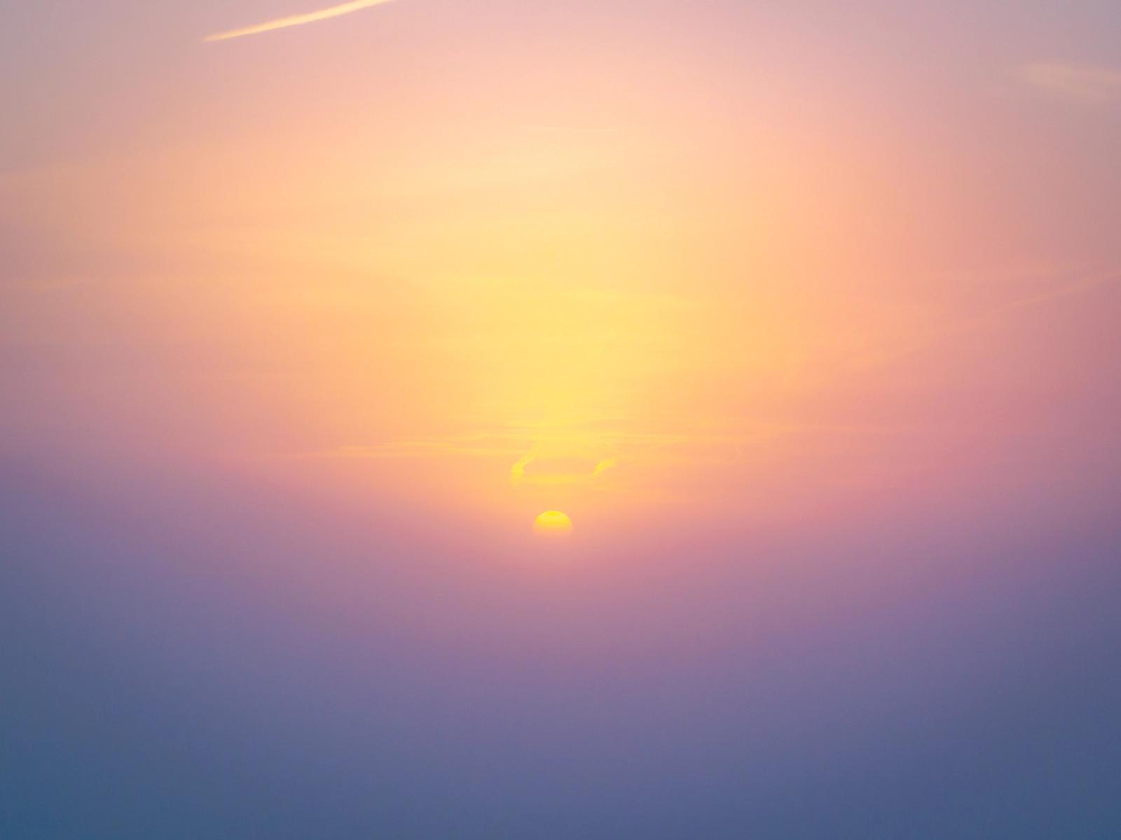 The setting sun drops beneath a thin band of cloud above the Thames Valley, its disc diffused by haze into a soft corona of amber and mauve. Captured by drone near Abingdon-on-Thames in early March, the image records a moment of atmospheric optical separation rather than a conventional sunset composition.