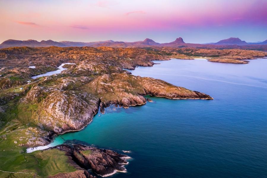 The incredible landscape of North West Scotland, here seen from above with my drone. The distant mountains, the calm blue ocean, clear pastel sky and white beaches below all combine together into a magical sunset capture of this dramatic landscape.
