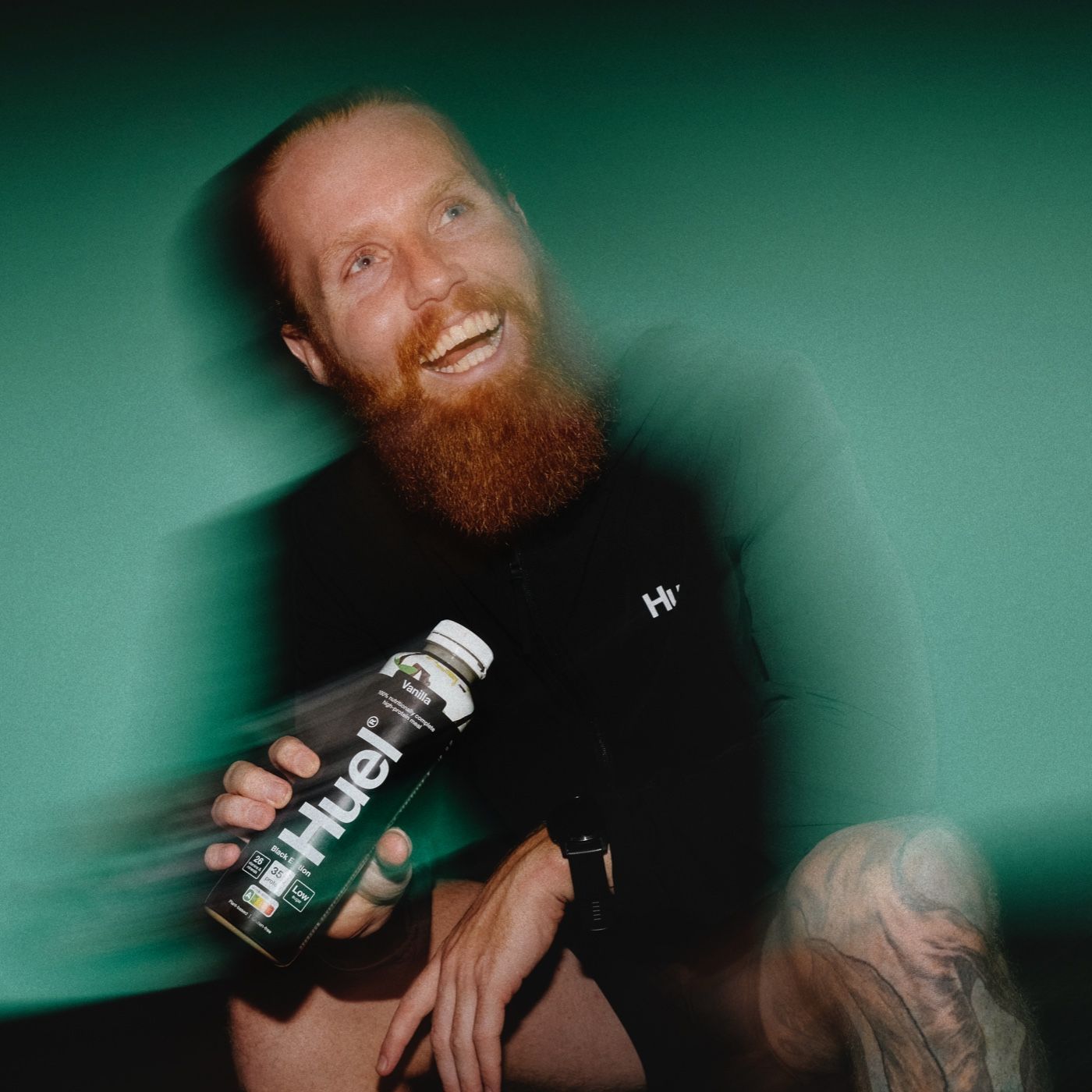 Motion-blur image of Russ Cook - the hardest geezer - holding a bottle of Huel ready-to-drink against a teal background
