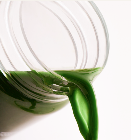 Green Huel Daily Greens liquid being poured from a clear shaker bottle
