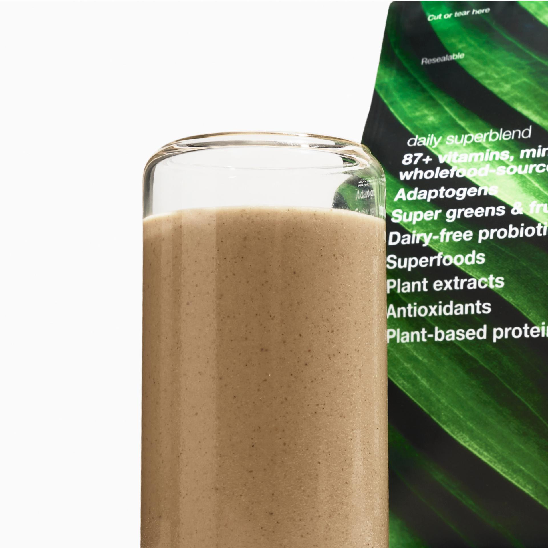 An image of prepared Superblend in a glass cup, with the Superblend pouch behind it.