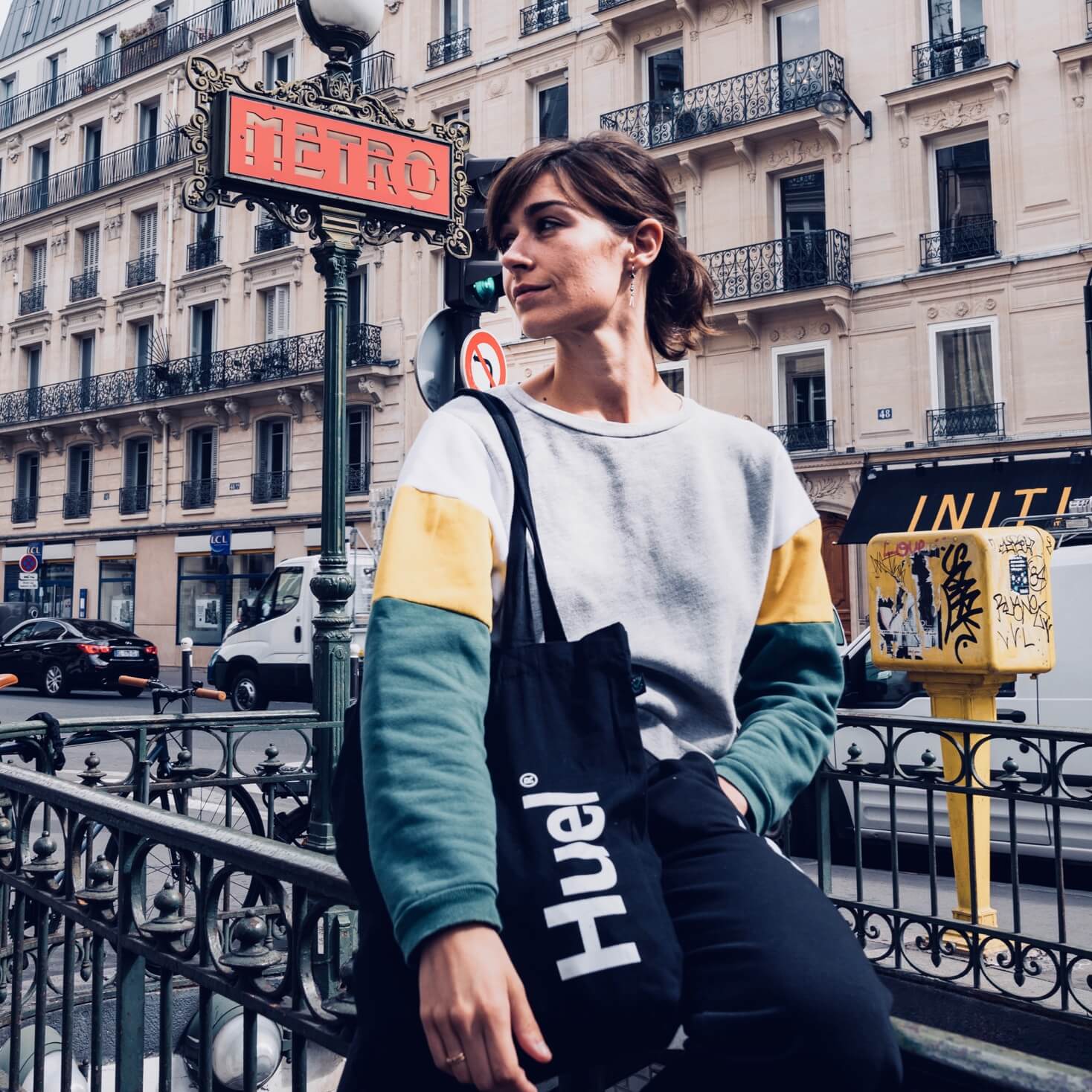 Woman stood by a Paris metro sign wearing a Huel tote bag