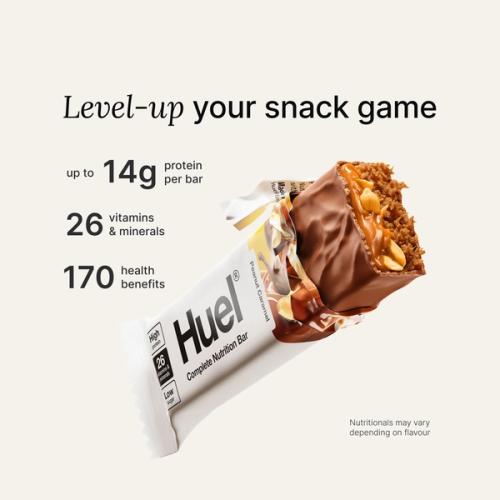 A Huel Complete Nutrition bar with a peanut and caramel filling, set against a beige-colour background