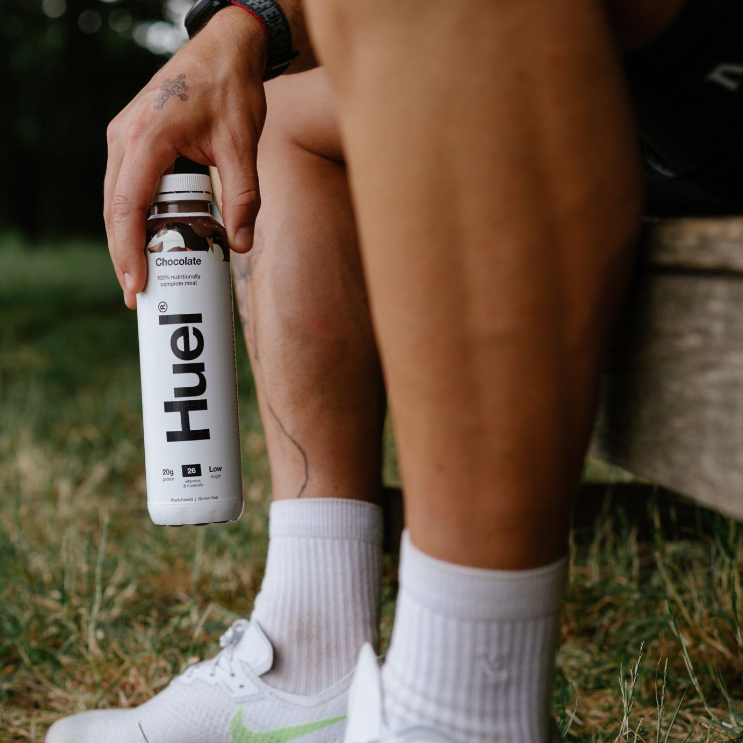 Man sitting down outside holding a bottle of Chocolate Ready-to-drink within one hand