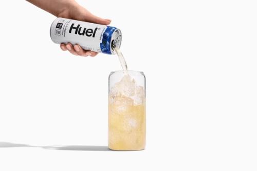 A man placing a can of Huel Daily A-Z Vitamins energy drink on a wooden park bench