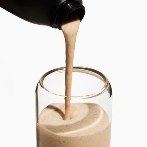 Shaker pouring Superblend into glass cup