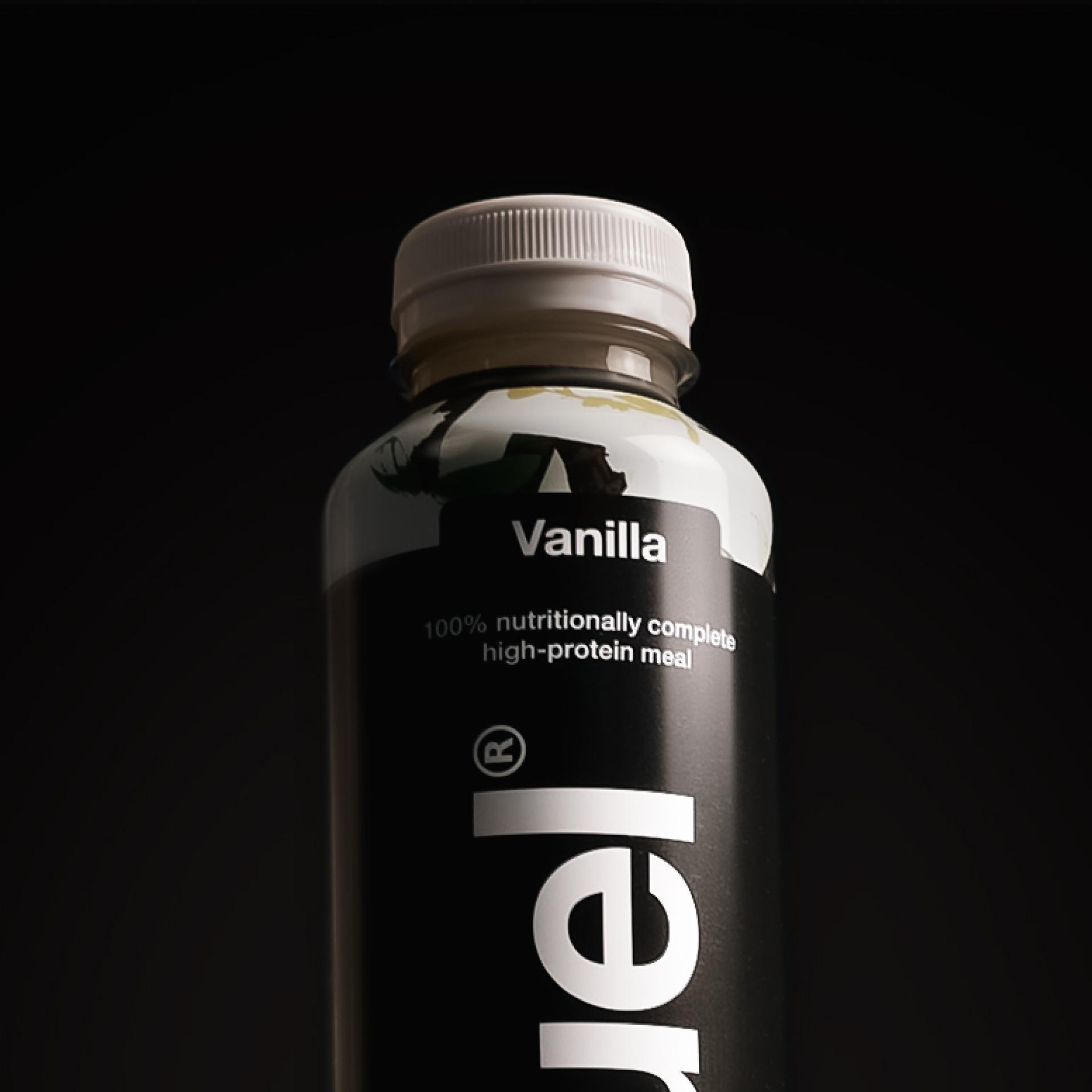 Top-down image of a glass of vanilla Huel Black Edition Ready-to-drink with ice, on a plain background