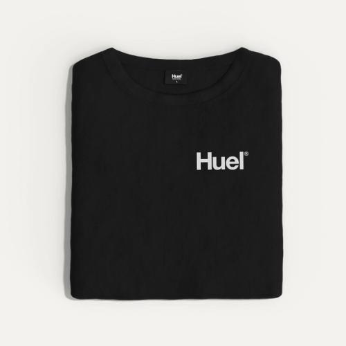 A folded black Huel t-shirt with a white 'Huel' logo on it, resting on a neutral surface