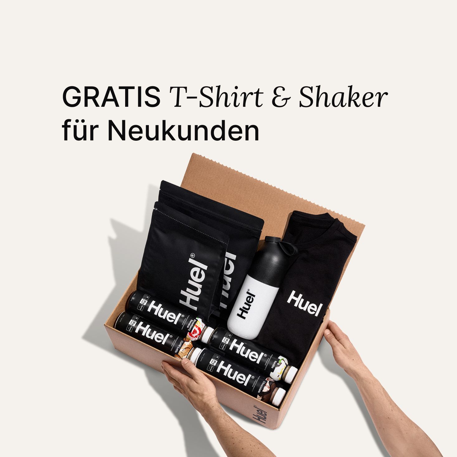 Offene braune Pappschachtel mit Huel Produkten und Accessoires, darunter ein schwarzes Huel-T-Shirt und ein Shaker