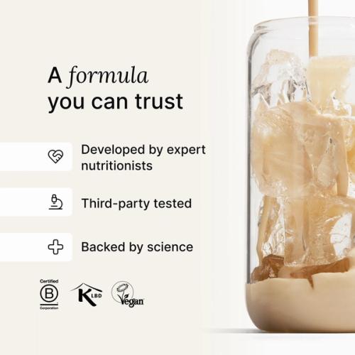 Huel vanilla shake being poured into a glass with ice, against a neutral background