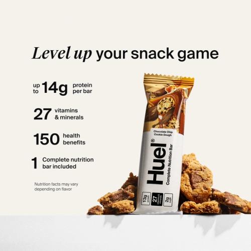 Huel Complete Nutrition bar propped against some cookies open on a neutral color background