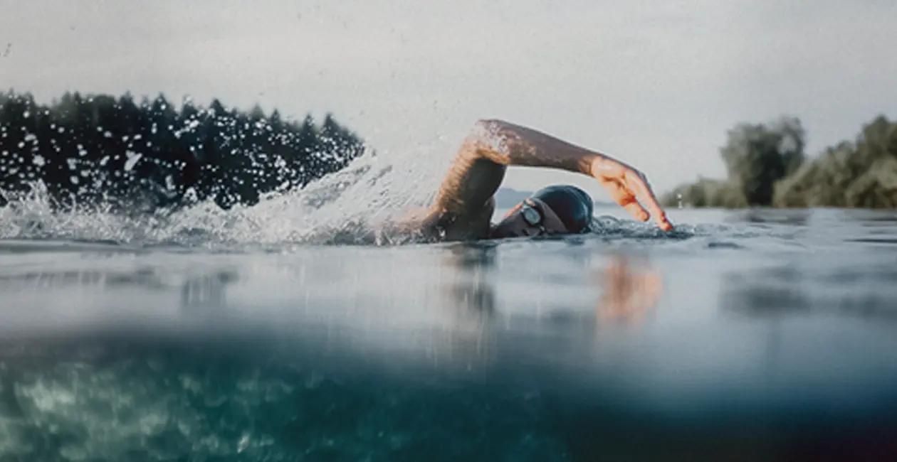 man swimming outside with trees in the background