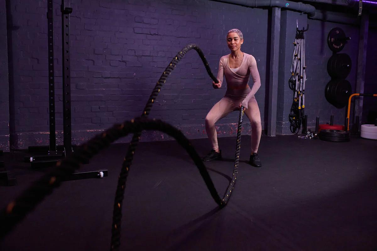 Woman using ropes for conditioning training at a gym