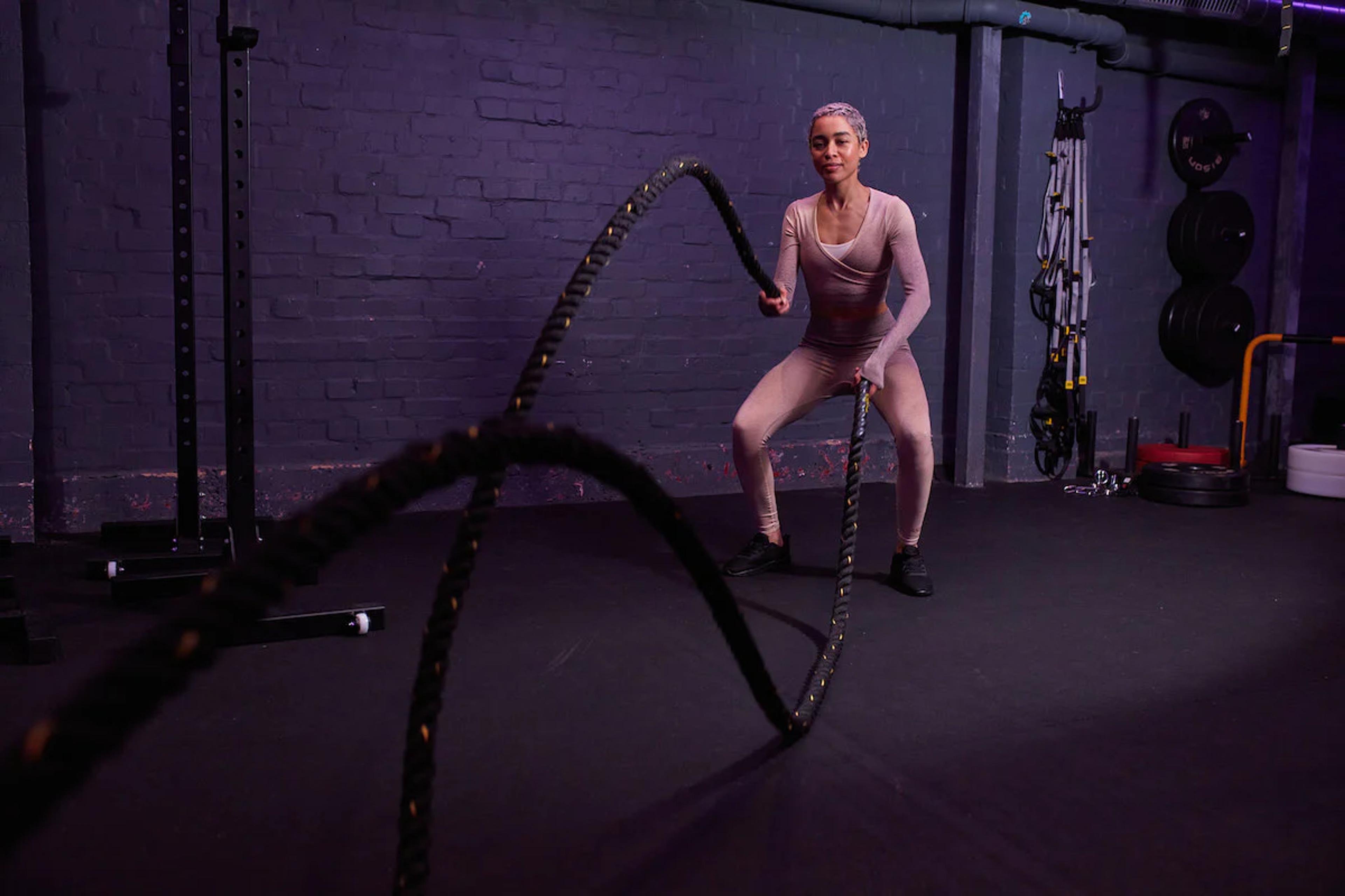 Woman using ropes for conditioning training at a gym