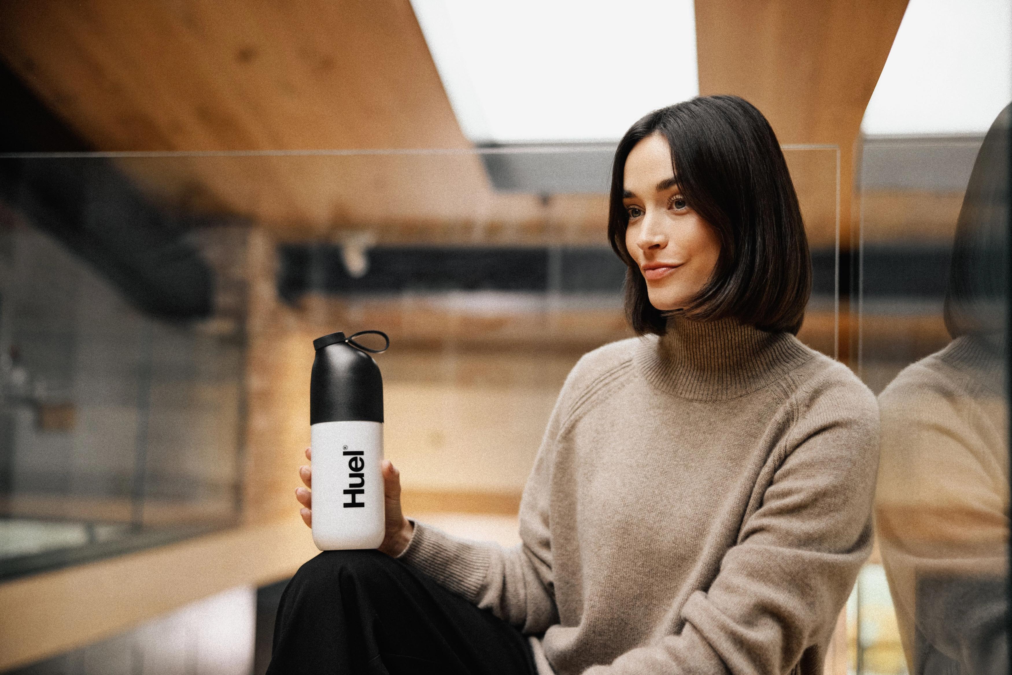 woman going downstairs in a modern styled apartment holding a huel shaker