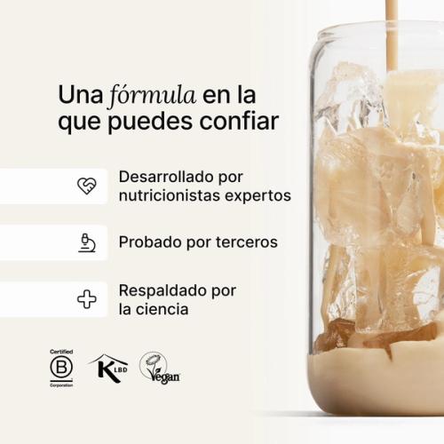 Huel vanilla shake being poured into a glass with ice, against a neutral background