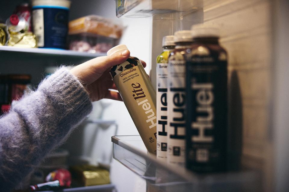 A person reaching for Huel from the fridge door