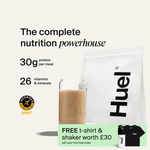 A bag of Huel professional powder next to a glass containing a Huel drink on a neutral background