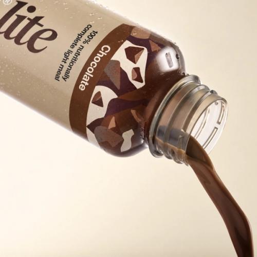 Huel chocolate pouring from a bottle of Huel Ready-to-drink lite on a beige background
