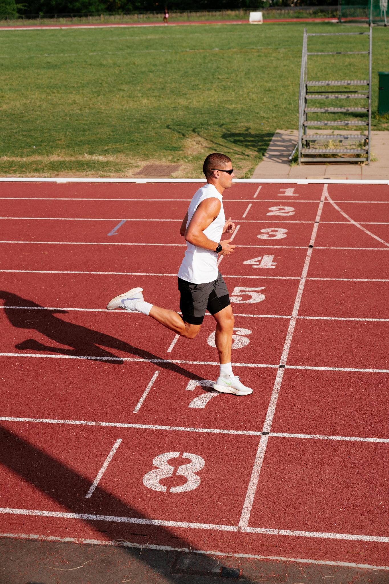 man running outside on a running track crossing the finish line