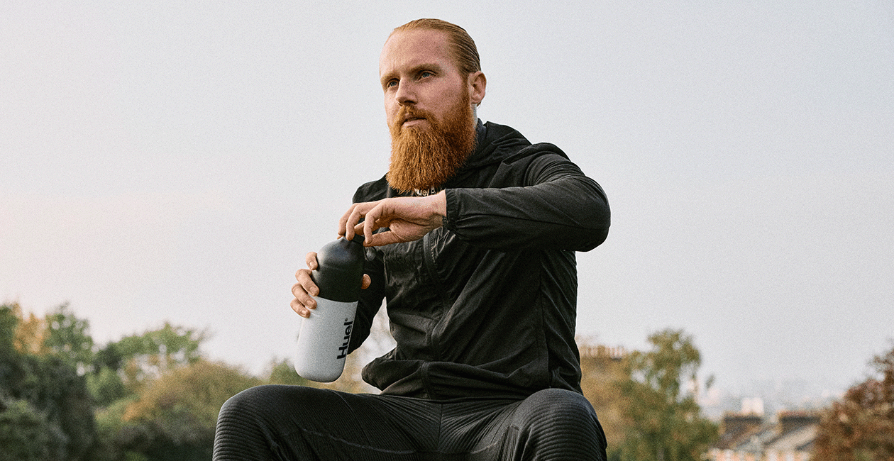 Russ Cook - The Hardest Geezer - sat outside unscrewing the cap on his Huel shaker