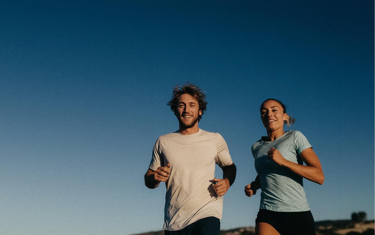 Man and woman running with a blue sky in the background