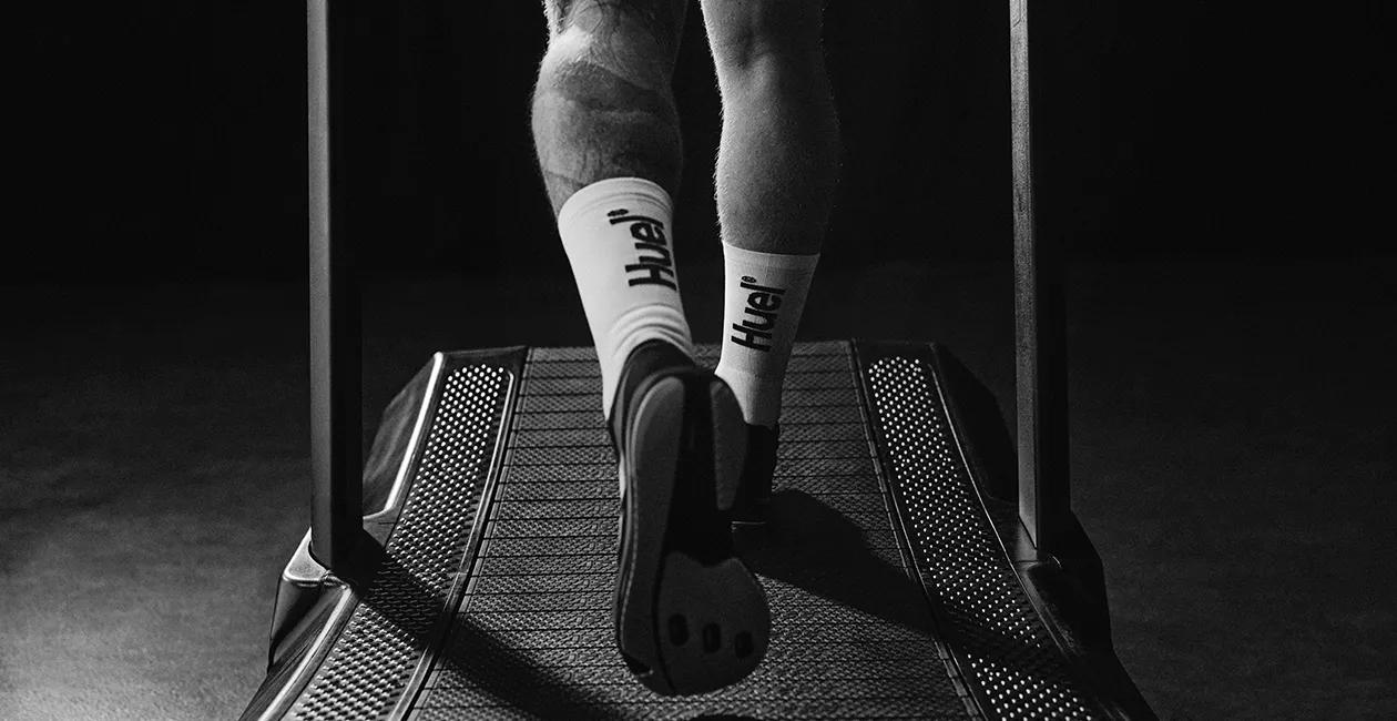 man on treadmill from behind showing from the knee down wearing Huel socks and running shoes