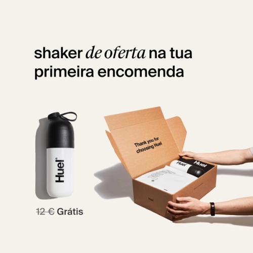 alguém segurando uma caixa de Huel contendo uma saqueta de pó branco, e um shaker preto e branco, num fundo neutro