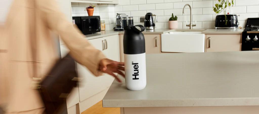 someone picking up a huel shaker off the side in the kitchen