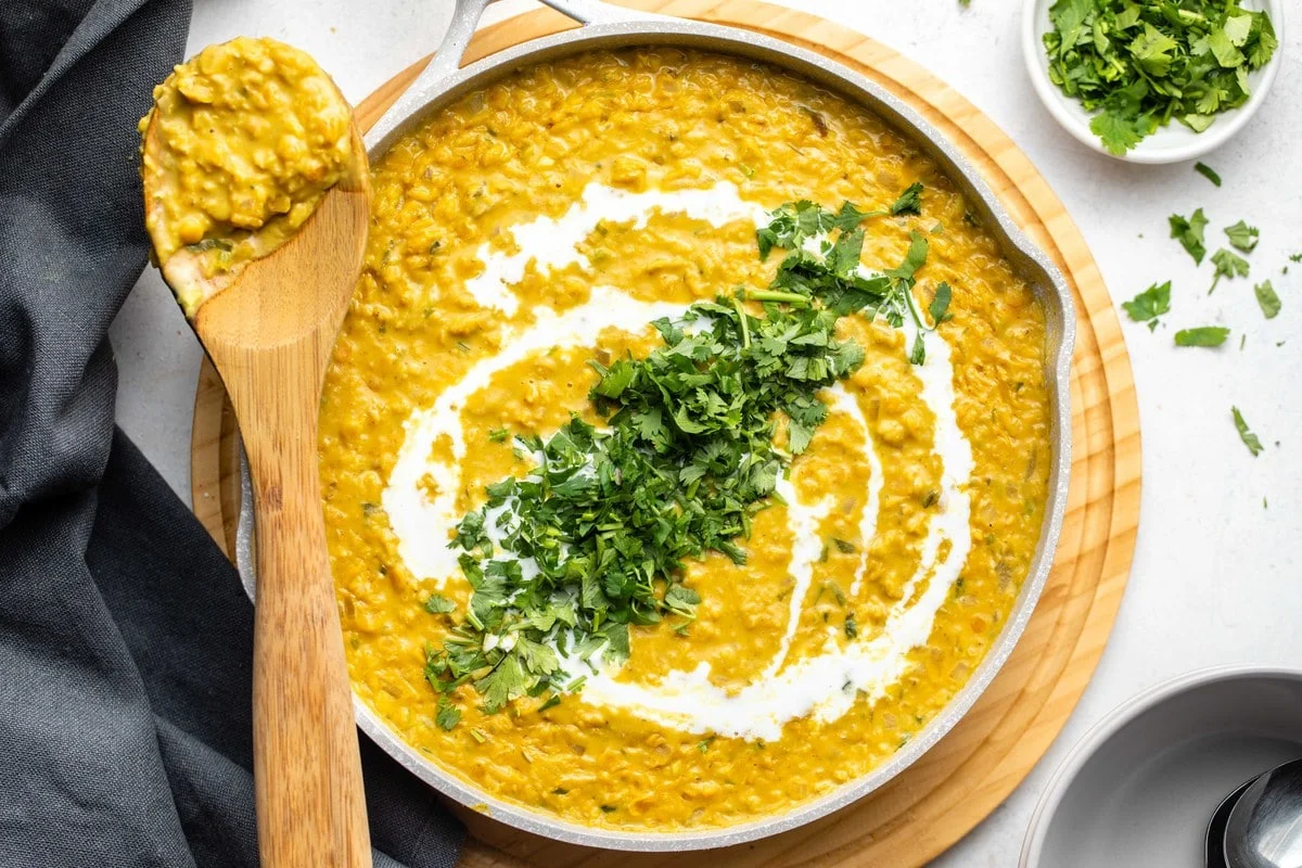 coconut and red lentil dhal in a pan with a wooden spoon