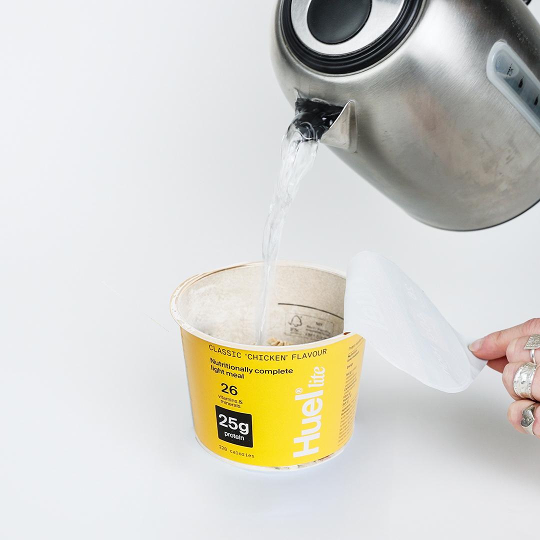 A Huel Lite Ramen pot with water being poured into it