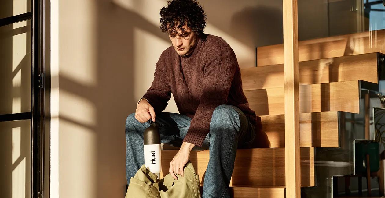 A man sat on stairs with a Huel shaker