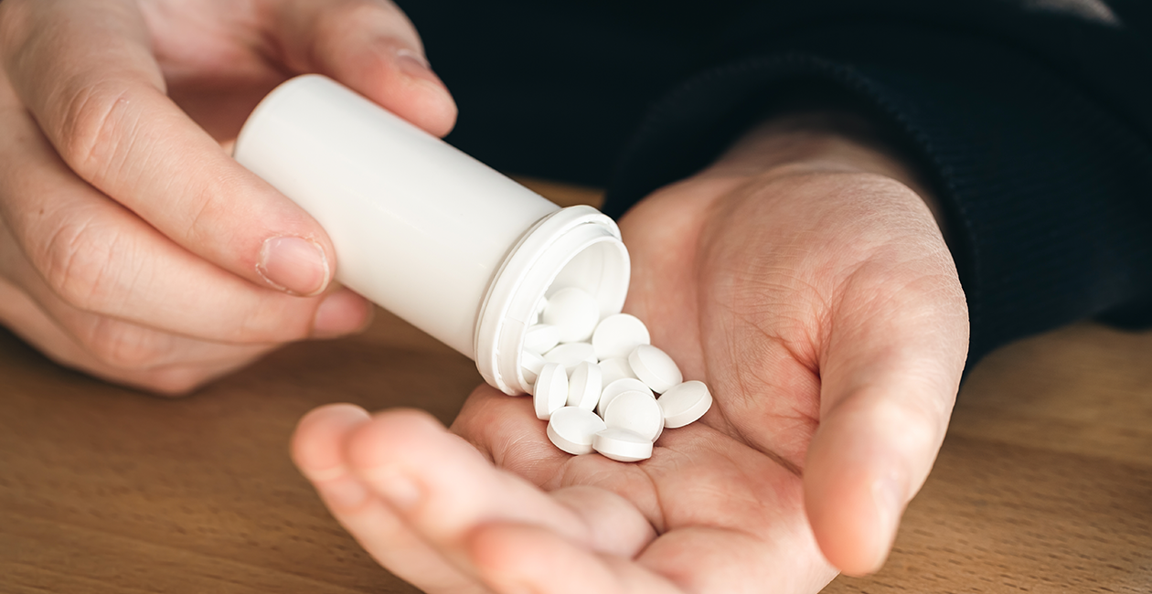 A man pouring out white tablets from a tube