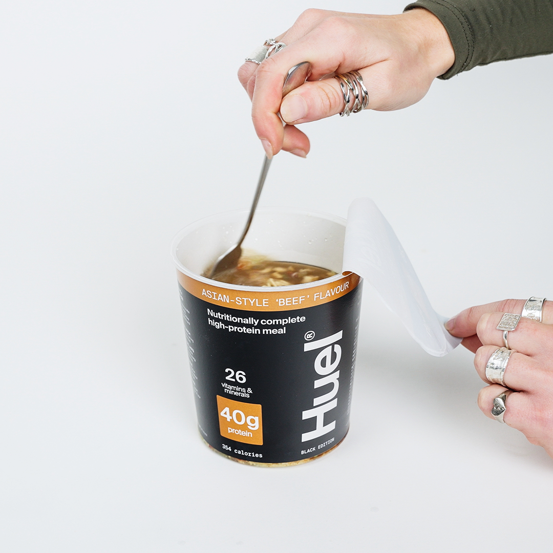 Someone stirring a full pot of Black Edition Ramen with a fork