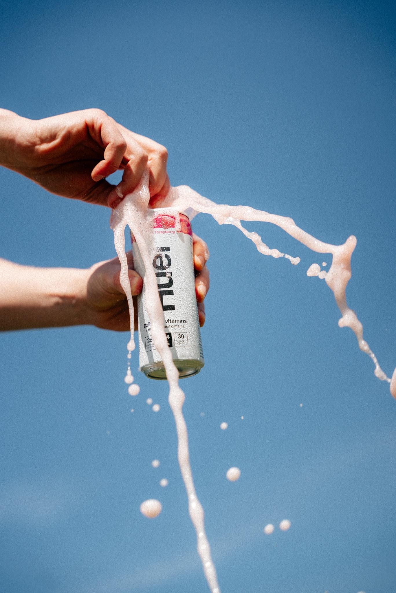 someone opening a Huel energy drink with a blue sky background