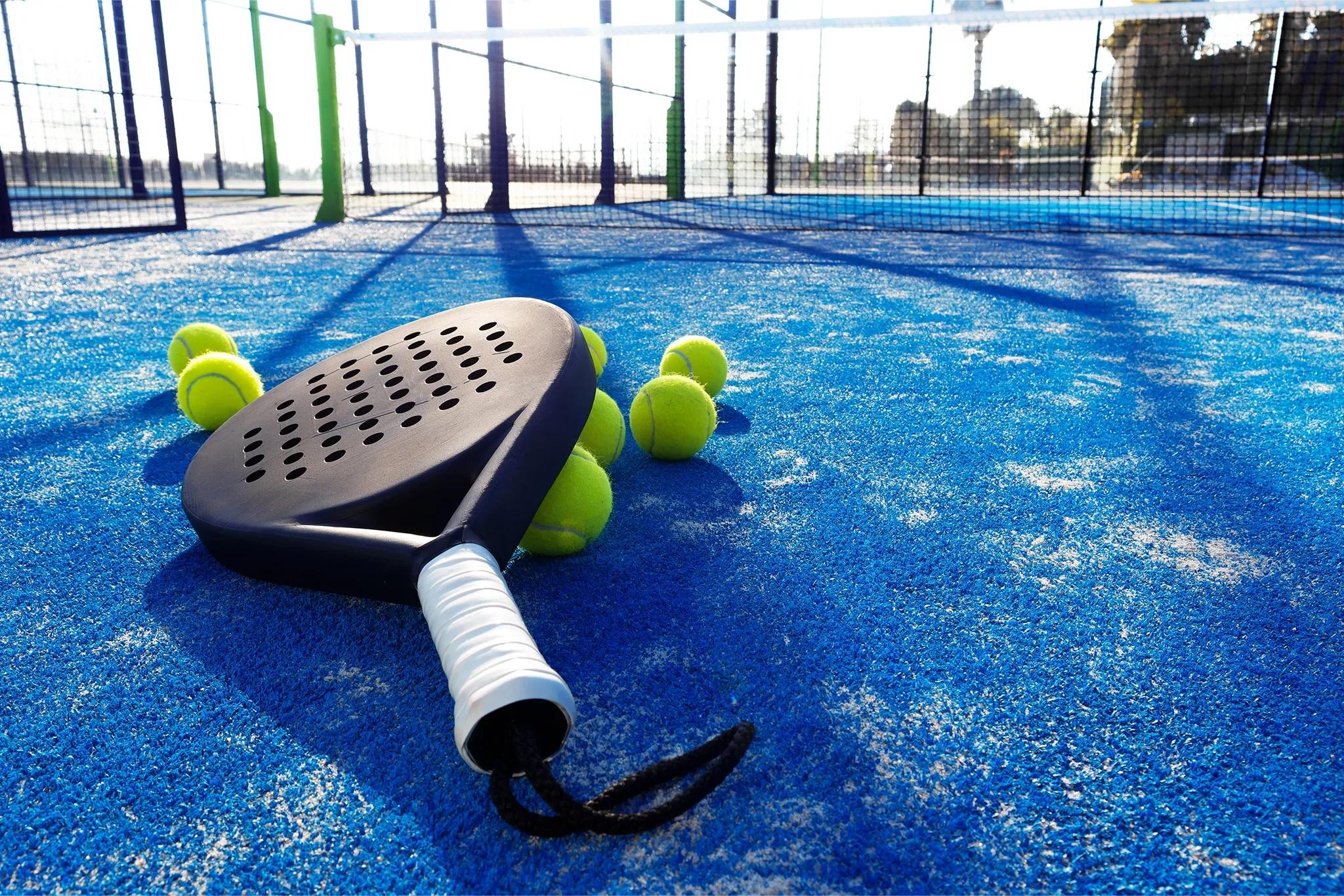 Padel racket resting on padel balls on a padel court