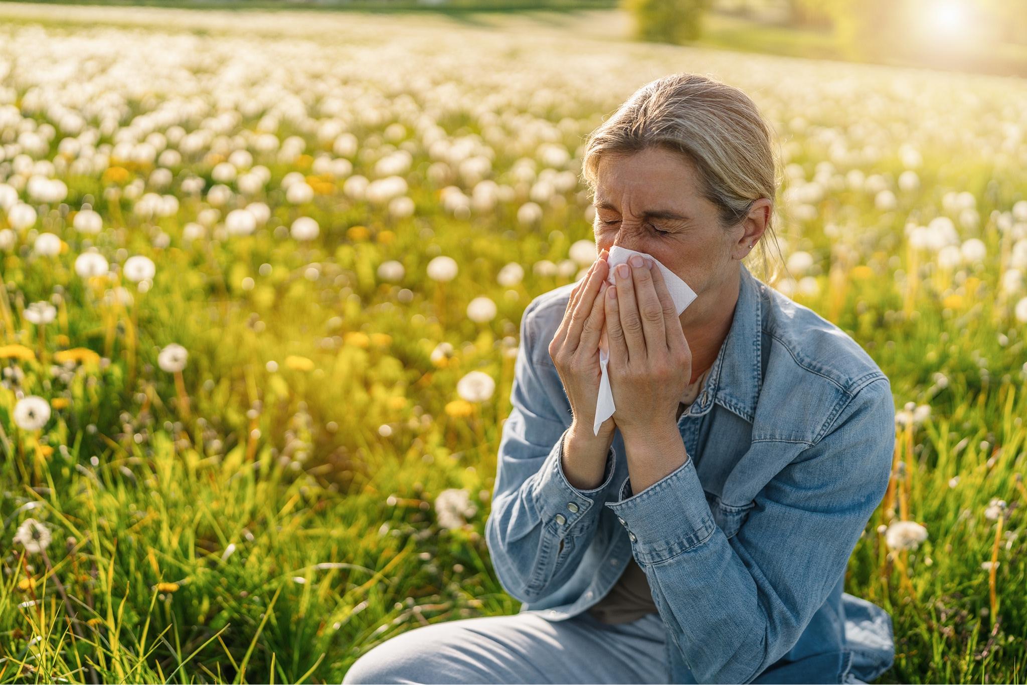 woman sat in a field blowing her nose