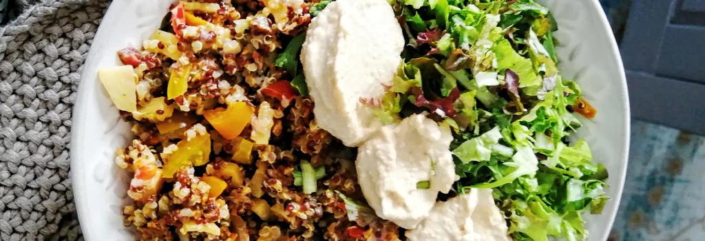 Vegan quinoa salad bowl with mushrooms, spinach, and hummus
