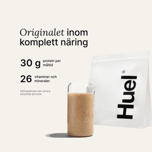 En påse Huel-pulver bredvid ett glas som innehåller en Huel-dryck på neutral bakgrund