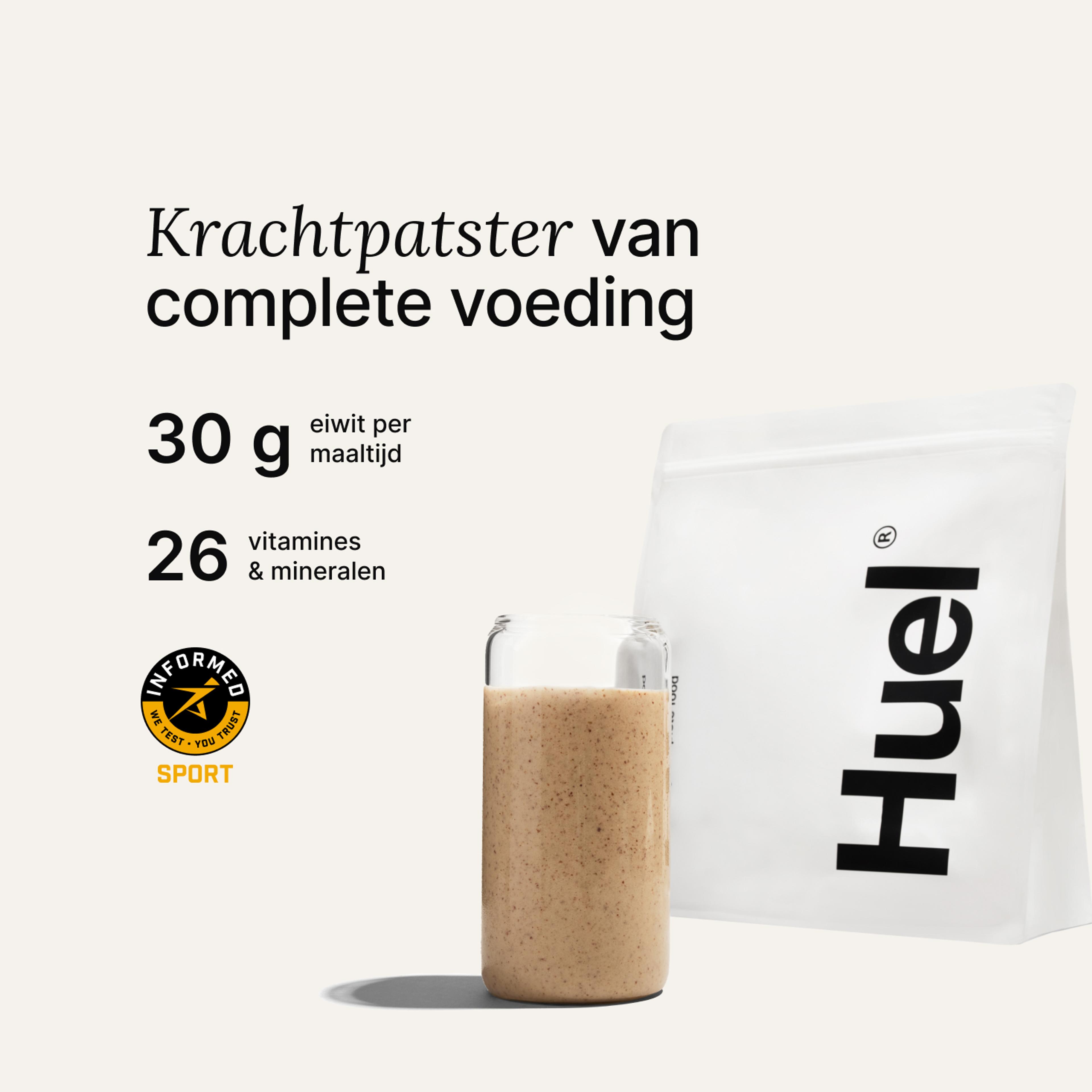 A bag of Huel powder next to a glass containing a Huel drink on a neutral background