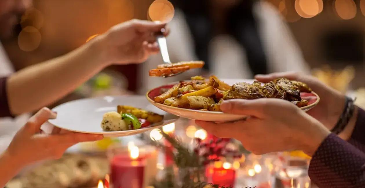 people serving a festive roast dinner on plates over a decorated table