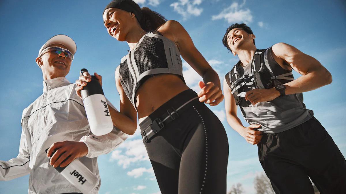 three people jogging outside while laughing and carrying huel shakers