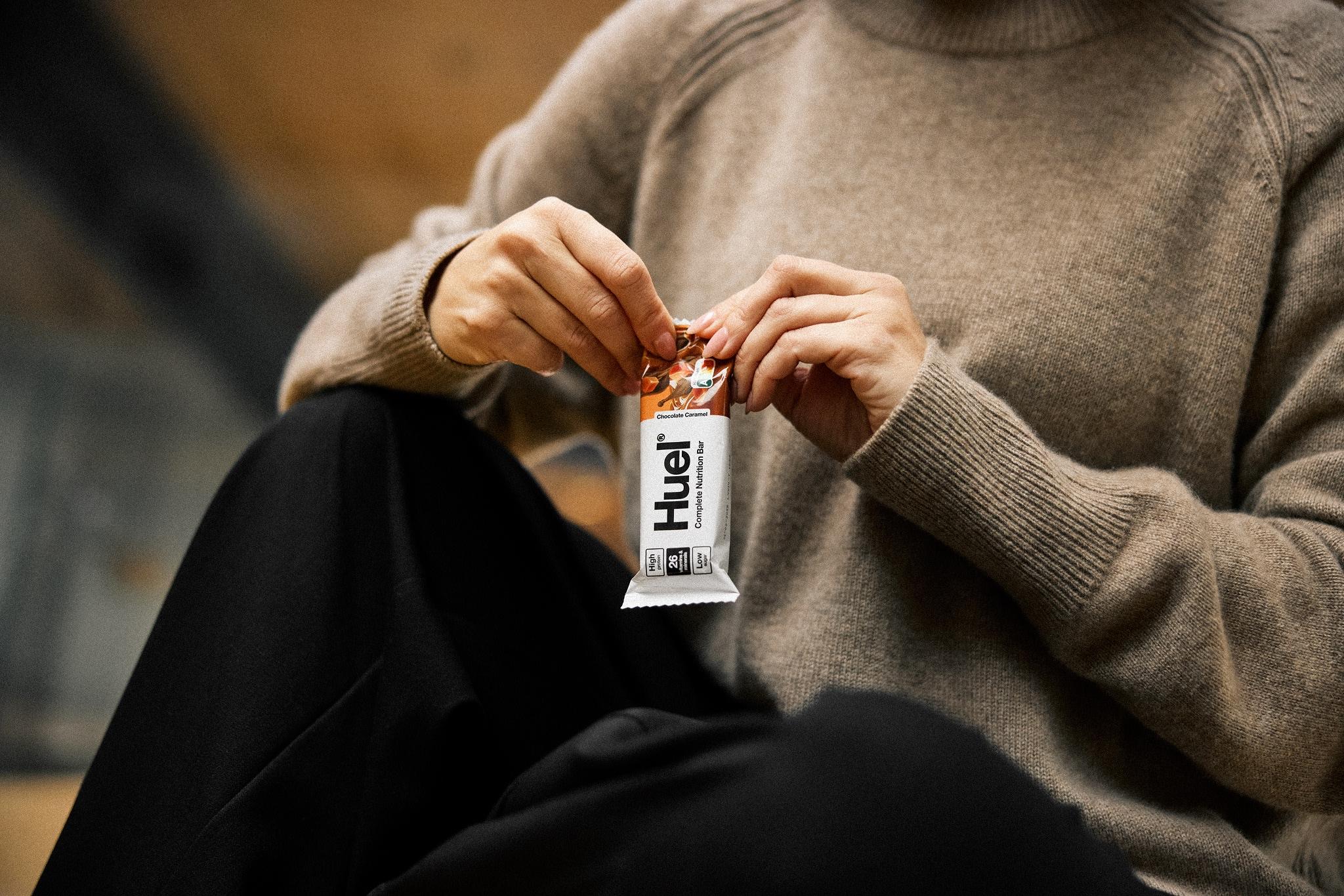 man in a sweater opening a huel complete nutrition bar